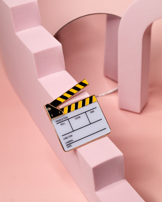 Black and Yellow film slate enamel pin with pink background