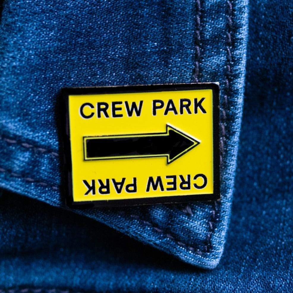 Crew Park black and yellow arrow film location sign enamel pin on a collar shirt