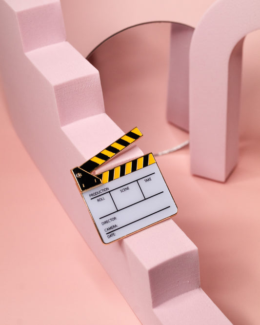 Black and Yellow film slate enamel pin with pink background 